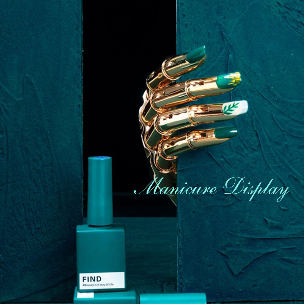Gold mannequin hand with green and white nail art against a dark teal background