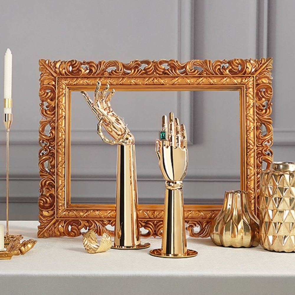Gold mannequin hand jewelry display stands styled with decorative frame and luxury accessories